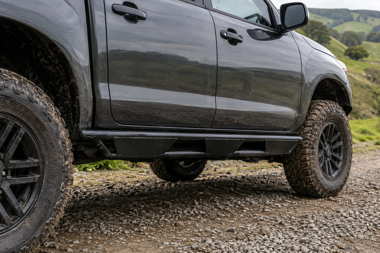 Heavy welded tube and plate rock sliders fitted along the sill of a 4WD ute