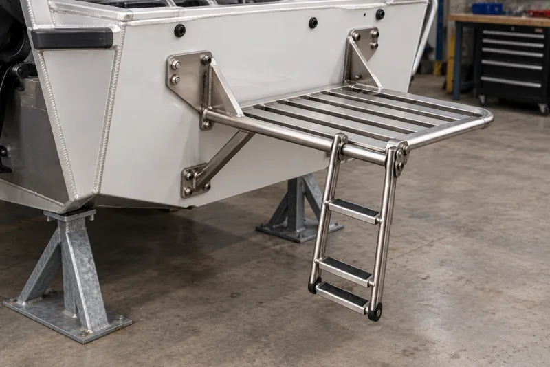 A stainless boarding platform bolted to a boat transom with support braces and a hinged ladder