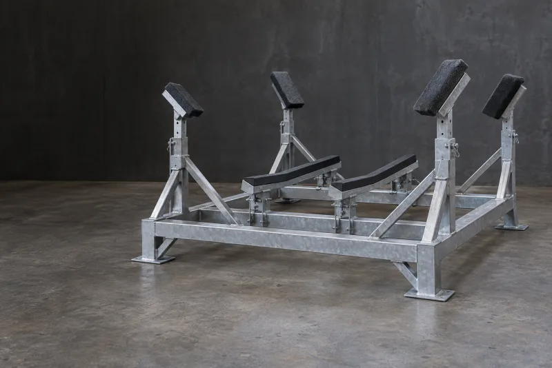 An empty braced metal boat cradle with adjustable padded hull supports and two lower padded rails