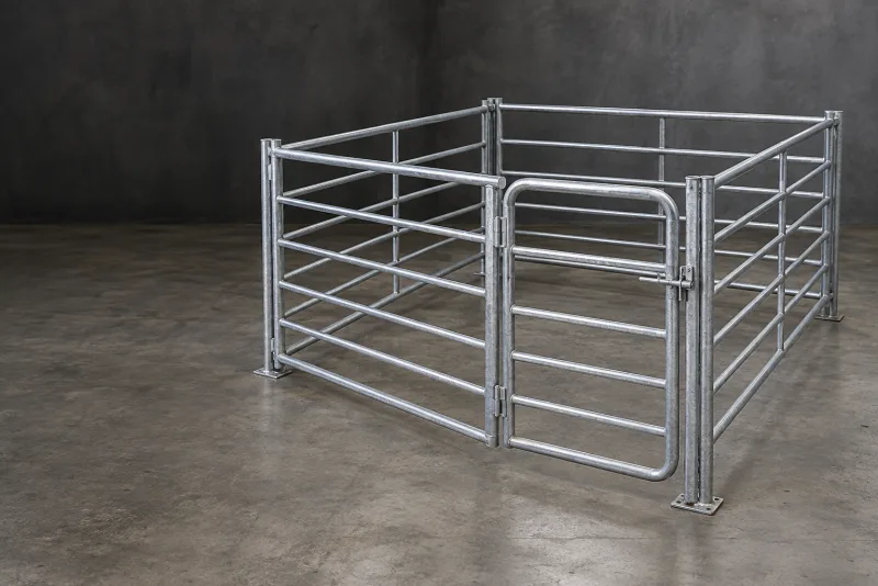 A galvanised livestock pen corner with mesh panels and a hinged access gate