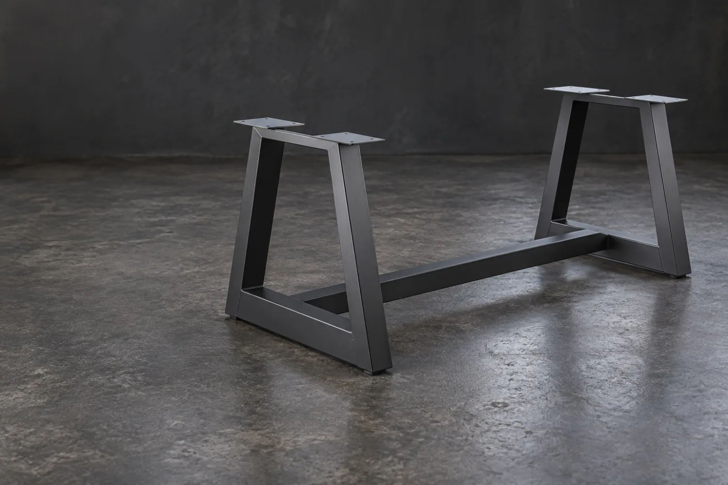 Concept illustration of a charcoal steel table base with two trapezoidal end frames and a connecting stretcher