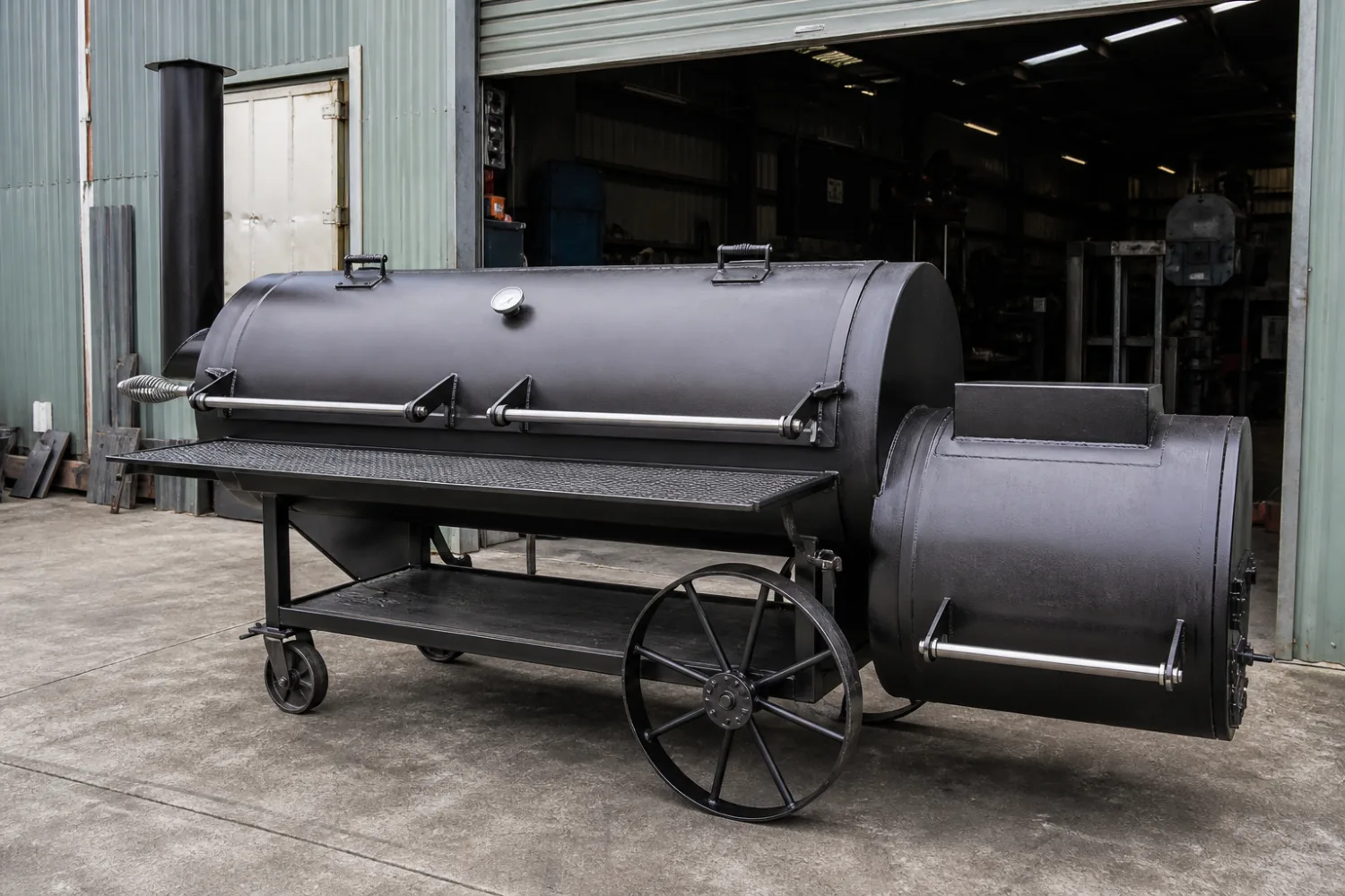 Custom fabricated heavy-plate offset BBQ smoker with a separate firebox and stainless racks on wheels, made by Specialised Stainless