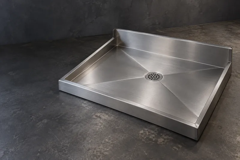 A stainless steel shower tray with wall upstands and a round drain