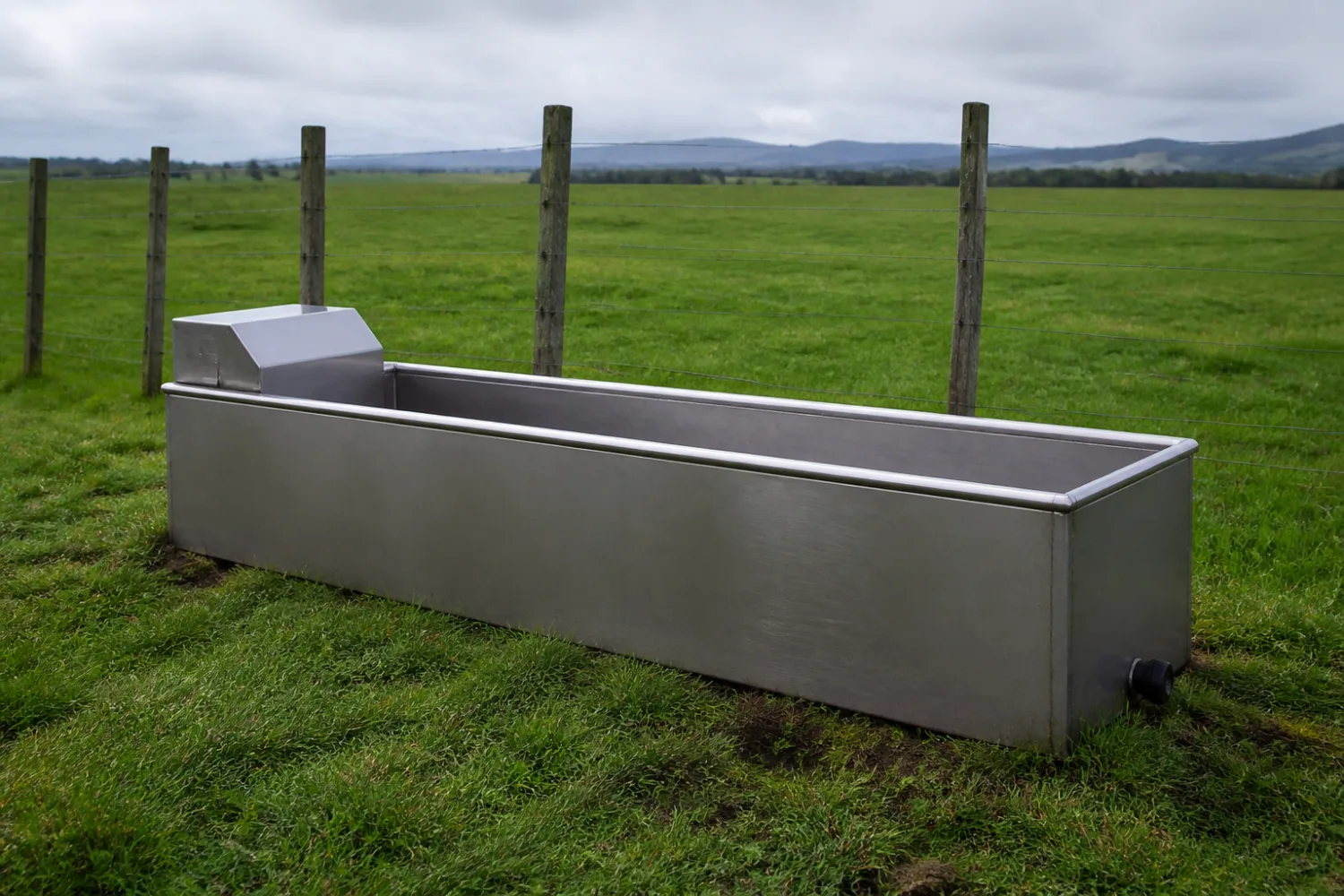 Custom fabricated stainless steel fence-line stock water trough with a float-valve housing in a New Zealand paddock, made by Specialised Stainless
