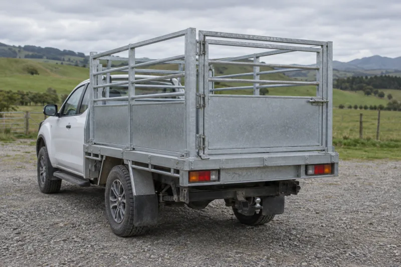 An all-metal livestock crate secured to a ute flat deck with its rear gate closed